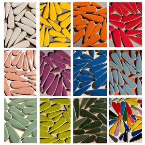 May include: A selection of teardrop-shaped ceramic tiles in a range of colours, including white, yellow, orange, red, pink, purple, blue, and green. The tiles are arranged in a grid, highlighting their glossy finish and distinctive shape.