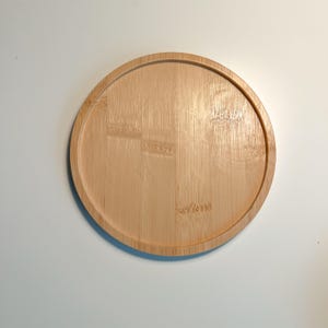 Op de afbeelding: Een ronde, lichtbruine houten dienblad met een glad oppervlak. Het dienblad is gemaakt van bamboe en heeft een natuurlijke houtnerf.