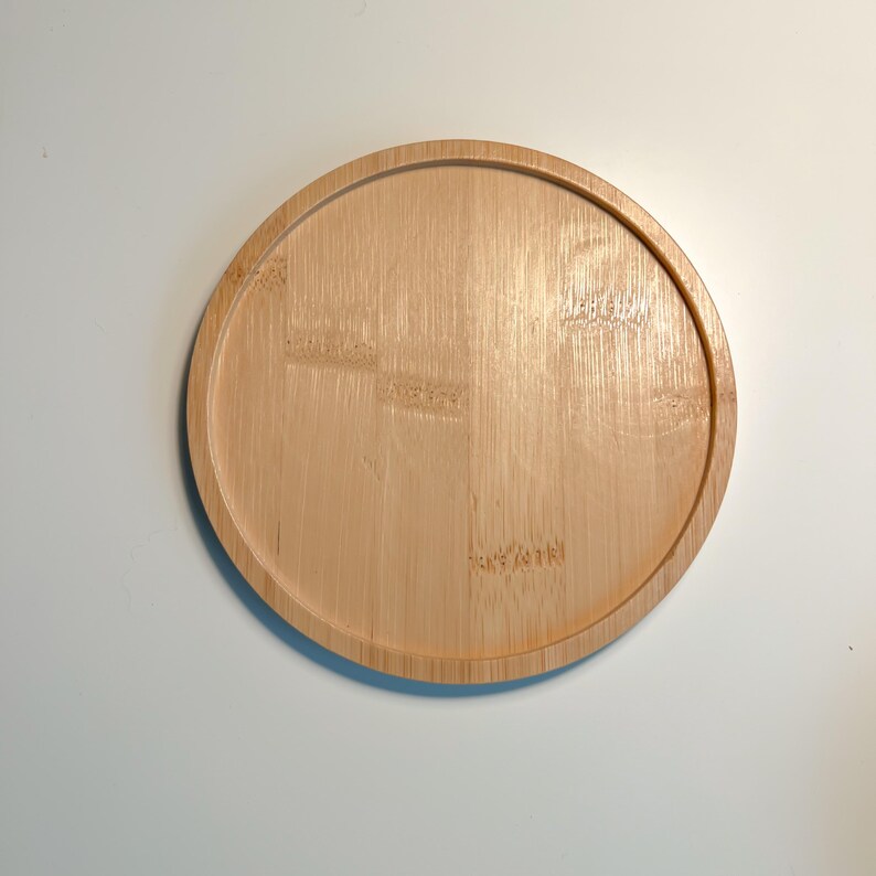 Op de afbeelding: Een ronde, lichtbruine houten dienblad met een glad oppervlak. Het dienblad is gemaakt van bamboe en heeft een natuurlijke houtnerf.