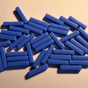 Könnte beinhalten: Eine Sammlung blauer Glasfliesen in rechteckiger Form. Die Fliesen sind in einem zufälligen Muster angeordnet.