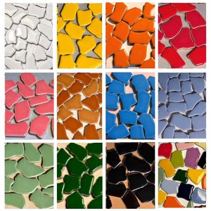 May include: A grid of irregularly shaped ceramic tiles in various colours. The tiles include white, yellow, orange, red, pink, brown, blue, green, and black. The glossy tiles reflect light, creating a vibrant display. Ideal for mosaic projects.