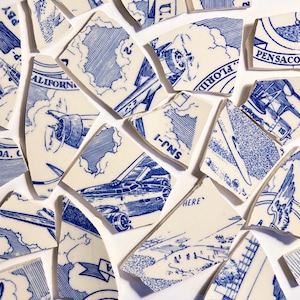 May include: A scattered arrangement of broken ceramic tiles featuring blue and white illustrations. The fragments show aeroplanes, clouds, and text fragments such as "PBY", "ALIFORN", and "FLORID". The pieces are set against a white background.