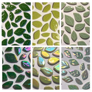 May include: Leaf-shaped ceramic tiles in shades of green and iridescent colours. The tiles are arranged on a white surface, highlighting their glossy texture and veining details. Ideal for mosaics or decorative projects.
