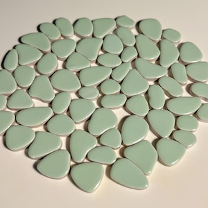 May include: A collection of light green ceramic tiles in various pebble shapes.