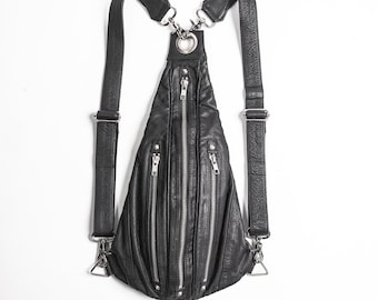 May include: A black teardrop-shaped backpack with a textured surface, featuring three vertical silver-toned metal zippers on the front, adjustable shoulder straps with metal clips, and a large silver ring at the top attachment point.