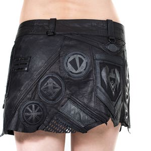 May include: A black leather mini skirt with various patches and embellishments. The skirt has a zipper closure and a belt loop.