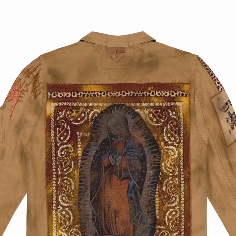 Puede incluir: Chaqueta color canela con un gran gr&aacute;fico en la espalda que presenta una imagen religiosa, un estampado de cachemira y detalles de estampado de leopardo. La chaqueta tiene parches y texto adicionales en las mangas. El estilo es una mezcla de streetwear e iconograf&iacute;a religiosa.