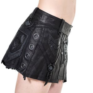 May include: A black leather skirt with a unique design featuring multiple straps, buckles, and decorative stitching. The skirt has a short, A-line silhouette.