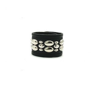 Op de afbeelding: Een zwarte leren armband met zilveren ovale studs. De armband is ongeveer 2,5 cm breed.