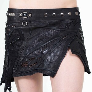 Könnte beinhalten: Ein schwarzer Lederrock mit einem geschichteten Design, inklusive einem Nietengürtel und einer Spitzenborte. Der Rock hat einen Used-Look mit Ausschnitten und ausgefransten Kanten.