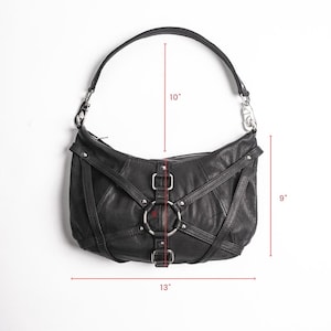 K&ouml;nnte beinhalten: Schwarze Schultertasche aus Leder mit geschwungener Form. Die Tasche hat silberfarbene Hardware, einschlie&szlig;lich Ringe und Schnallen. Der Riemen misst 25 cm, die H&ouml;he betr&auml;gt 23 cm und die Breite 33 cm.