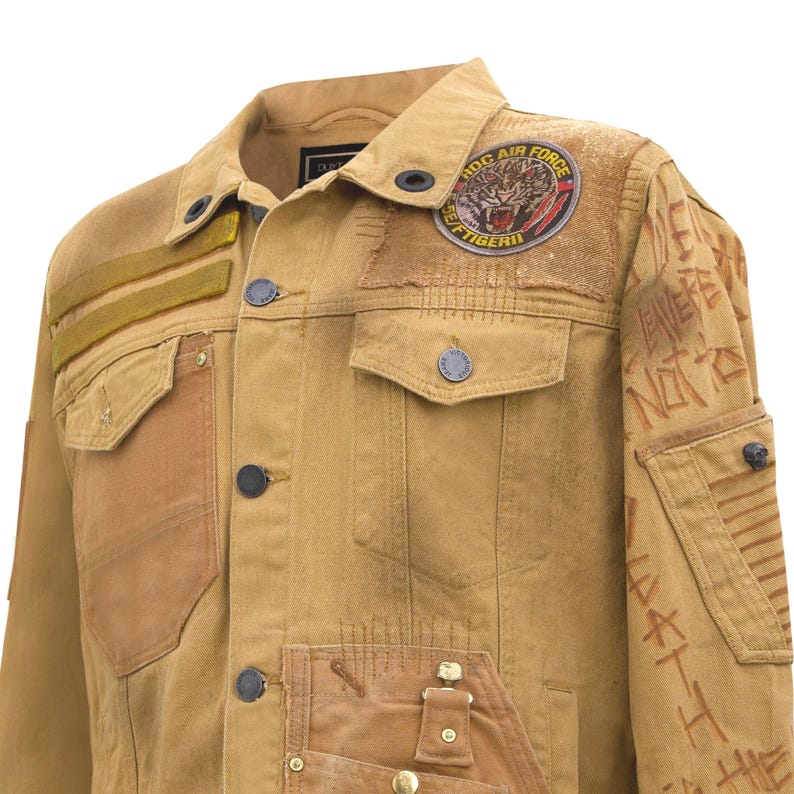 Puede incluir: Chaqueta vaquera color canela con m&uacute;ltiples parches y adornos. Presenta un parche de tigre "ROC AIR FORCE", detalles cosidos y texto en la manga. Incluye cierres de bot&oacute;n y varios dise&ntilde;os de bolsillo. Una prenda &uacute;nica de inspiraci&oacute;n vintage.