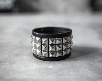 Brazalete de cuero negro con tachuelas piramidales de plata estilo punk rock