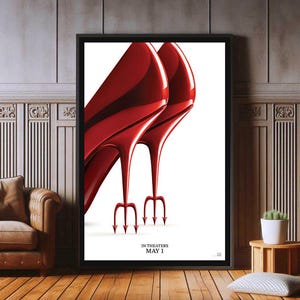 Könnte beinhalten: Gerahmtes Poster mit zwei glänzenden, roten High Heels mit dreizackförmigen Absätzen. Der Text "IN THEATERS MAY 1" steht unten. Das Bild ist vor einem weißen Hintergrund.