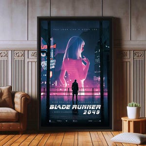 Op de afbeelding: Een ingelijste Blade Runner 2049 filmposter met een grote, gloeiende roze silhouet van een persoon achter een donkere figuur in een stadslandschap. De tekst luidt YOU LOOK LIKE A GOOD JOE, RYAN GOSLING, HARRISON FORD, BLADE RUNNER 2049, DENIS VILLENEUVE.