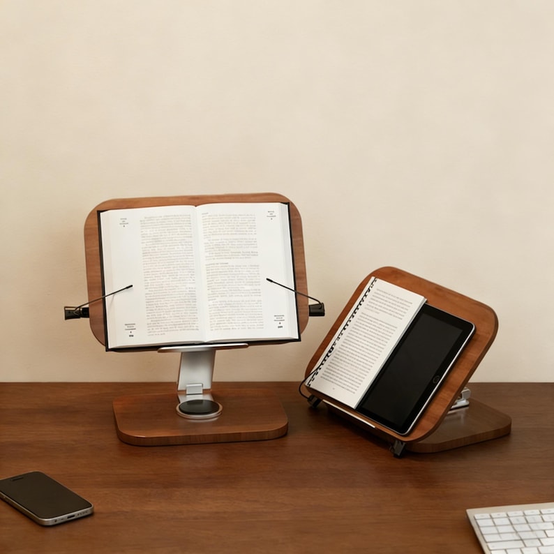 May include: Two wooden book stands with adjustable metal supports. One holds an open book, the other a notebook and tablet. The stands have a dark wood finish and are on a wooden surface.