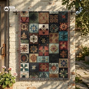 May include: A decorative throw blanket with a patchwork design of square tiles in various colors, including red, blue, and brown. The blanket is fringed and hung on a rod against a brick wall. The text "100% NATURAL" is visible.