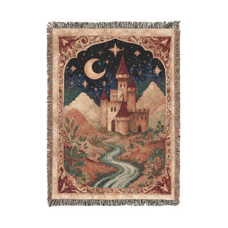 May include: A rectangular woven throw blanket featuring a detailed tapestry design of a castle under a night sky with a crescent moon and stars. The scene includes mountains, a winding river, and foliage, all framed by a decorative border with fringe.