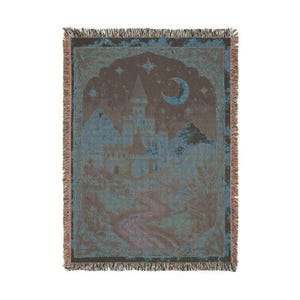 May include: A woven throw blanket featuring a dark brown and teal color palette. The design depicts a castle silhouette under a crescent moon and stars, with a winding path leading through a landscape of trees, finished with a fringed edge.