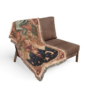 May include: A woven throw blanket featuring a detailed tapestry design of a tall tower, a crescent moon, and stars against a dark blue night sky, surrounded by ornate red and gold floral borders with fringed edges on all sides.