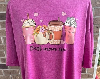 Op de afbeelding: Een roze T-shirt met een afbeelding van vier koffiedrankjes en de tekst "Best mom ever".