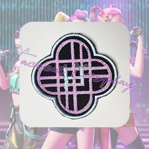 May include: Embroidered patch with a four-leaf clover design. The patch features a black clover shape with a light purple grid pattern and a white and light blue border. The text "ace factory play" is visible on the patch.