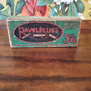May include: Vintage green and red Rawlplugs box with the text "Rawlplugs" in a circular design. The box also features the text "Household Outfit No. 8" and the number "36". The box is rectangular and appears to be made of cardboard.