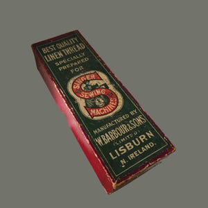 May include: A vintage Singer Sewing Machines linen thread box. The box is rectangular with a red base and a dark green top. Text on the box includes "Best Quality Linen Thread" and "Singer Sewing Machines". Manufactured by W. Barbour & Sons, Lisburn, N. Ireland.
