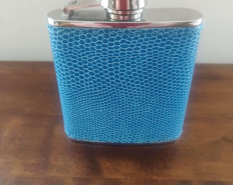 May include: A blue leather-covered flask with a silver top and a hinged cap.