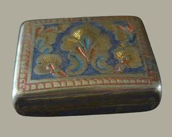 May include: A rectangular, antique brass box with an ornate floral design. The box features a blue background with gold, red, and turquoise accents. The edges are lined with a red, textured border. The box is likely used for storing small items.
