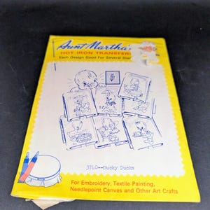 May include: A yellow Aunt Martha's hot iron transfer packet titled 3740--Ducky Ducks. The front features blue line art illustrations of ducklings performing daily activities, along with text for embroidery, textile painting, and needlepoint crafts.