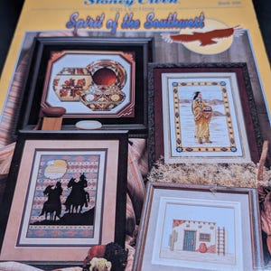 May include: A collection of framed cross-stitch patterns featuring Southwestern themes. The designs include Native American figures, pottery, and desert landscapes. The cover reads "Stoney Creek Collection Spirit of the Southwest."