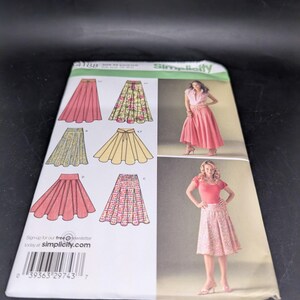 Peut inclure: Un patron de couture Simplicity présentant différents modèles de jupes. Le patron comprend des illustrations de différents styles de jupes, y compris des jupes trapèzes et froncées, dans différentes couleurs et motifs. La couverture montre également deux femmes portant les jupes.