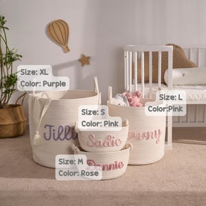 May include: Four off-white woven rope storage baskets of varying sizes. The XL basket features the purple name Jillie, the L basket has the pink name Lowry, the S basket has the pink name Sadie, and the M basket has the rose name Dannie.