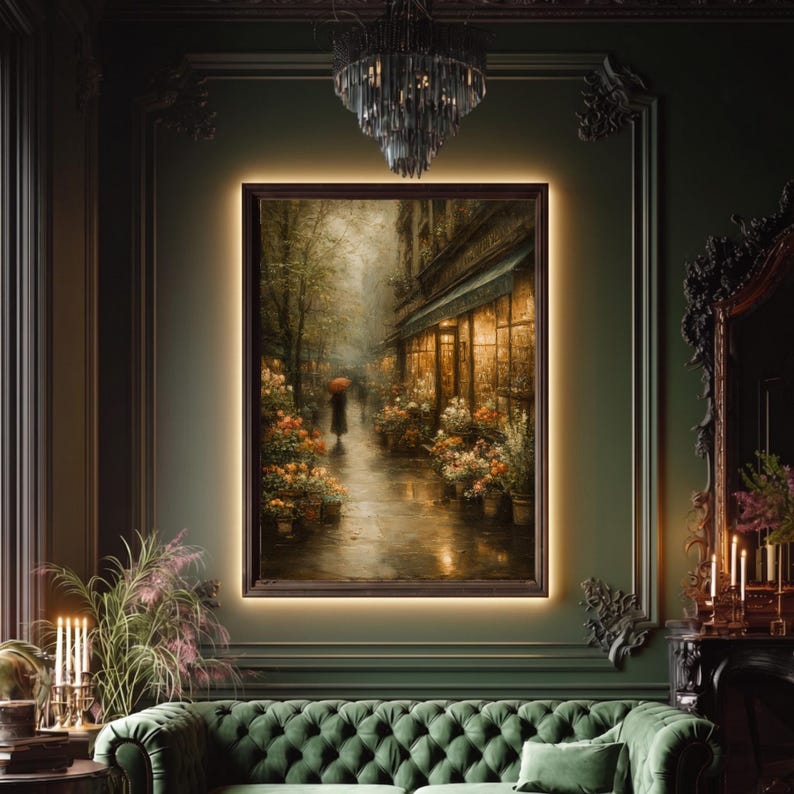 May include: A rectangular framed wall art piece depicting a rainy street scene with a person holding a red umbrella walking past a flower shop. The painting features warm golden light emanating from the shop windows against a dark, moody backdrop.