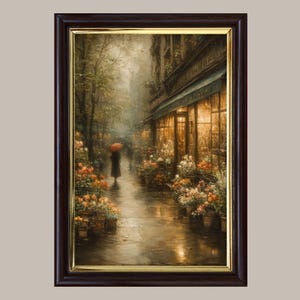 May include: A framed wall art print depicting a rainy city street scene at dusk. A figure with a red umbrella walks past a storefront illuminated by warm golden light, surrounded by potted flowers in shades of orange, white, and yellow.