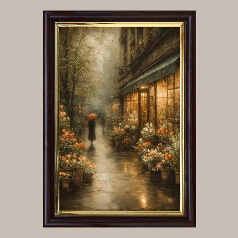 May include: A framed wall art print depicting a rainy city street scene at dusk. A figure with a red umbrella walks past a storefront illuminated by warm golden light, surrounded by potted flowers in shades of orange, white, and yellow.