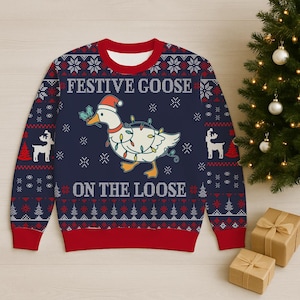 Könnte beinhalten: Marineblauer Pullover mit einem festlichen Gänsemotiv. Die Gans trägt einen Weihnachtsmannhut und ist mit Lichterketten geschmückt. Der Text "FESTIVE GOOSE ON THE LOOSE" ist zu sehen. Rote und weiße Akzente vervollständigen den festlichen Look.