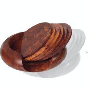 Peut inclure: Un bol en bois avec un ensemble de dessous de verre assortis. Le bol et les dessous de verre sont en bois brun foncé. Le bol a un design lisse et incurvé, et les dessous de verre sont ronds et empilés.