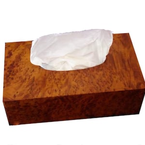 Peut inclure: Un distributeur de mouchoirs rectangulaire en bois de loupe brun, avec un motif de grain visible. Des mouchoirs blancs dépassent du dessus. Le boîtier a un design simple et élégant, adapté à la maison ou au bureau.
