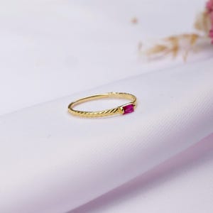 Può includere: Un anello d'oro con una fascia attorcigliata e una singola pietra rettangolare rosa.