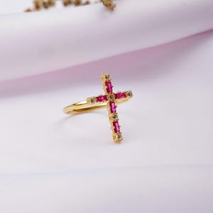 Peut inclure: Une bague en or avec un motif de croix rose et blanche. La croix est composée de petites pierres carrées.