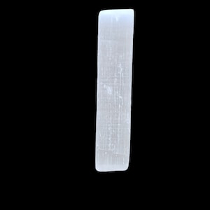 May include: A white selenite crystal wand, rectangular in shape, set against a black backdrop. The crystal has a polished surface with natural striations. The wand is displayed vertically, highlighting its elongated form.