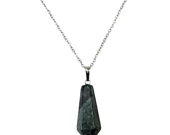 Puede incluir: Un collar de cadena plateada con un colgante geométrico verde oscuro. El colgante tiene una forma larga y facetada con una base puntiaguda. El collar se muestra sobre un fondo blanco.