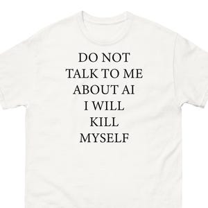 Op de afbeelding: Wit t-shirt met de zwarte tekst "DO NOT TALK TO ME ABOUT AI I WILL KILL MYSELF" gecentreerd op de voorkant. Het shirt heeft een ronde hals en korte mouwen.