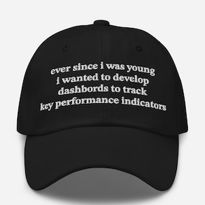May include: Black baseball cap with white embroidered text: "ever since I was young I wanted to develop dashboards to track key performance indicators." The cap has a curved brim and an adjustable strap.