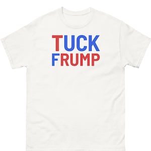 May include: White t-shirt with the text "TUCK FRUMP" in red and blue block letters. The shirt is a short-sleeved, crew neck style.