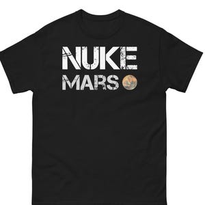 May include: Black t-shirt with the white text "NUKE MARS" and a graphic of the planet Mars. The text has a distressed, worn look. The shirt is made of a soft material.