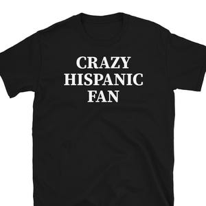 May include: A white ceramic mug with a black handle and the text "But First, Coffee" in a bold, black font. The mug is set against a blurred background, suggesting a cozy setting.