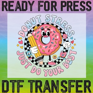 May include: A DTF transfer design featuring a cartoon donut with a pencil, surrounded by the text "Donut Stress, Just Do Your Best." The donut is pink with sprinkles, a black and white checkered border, and other cartoon characters.